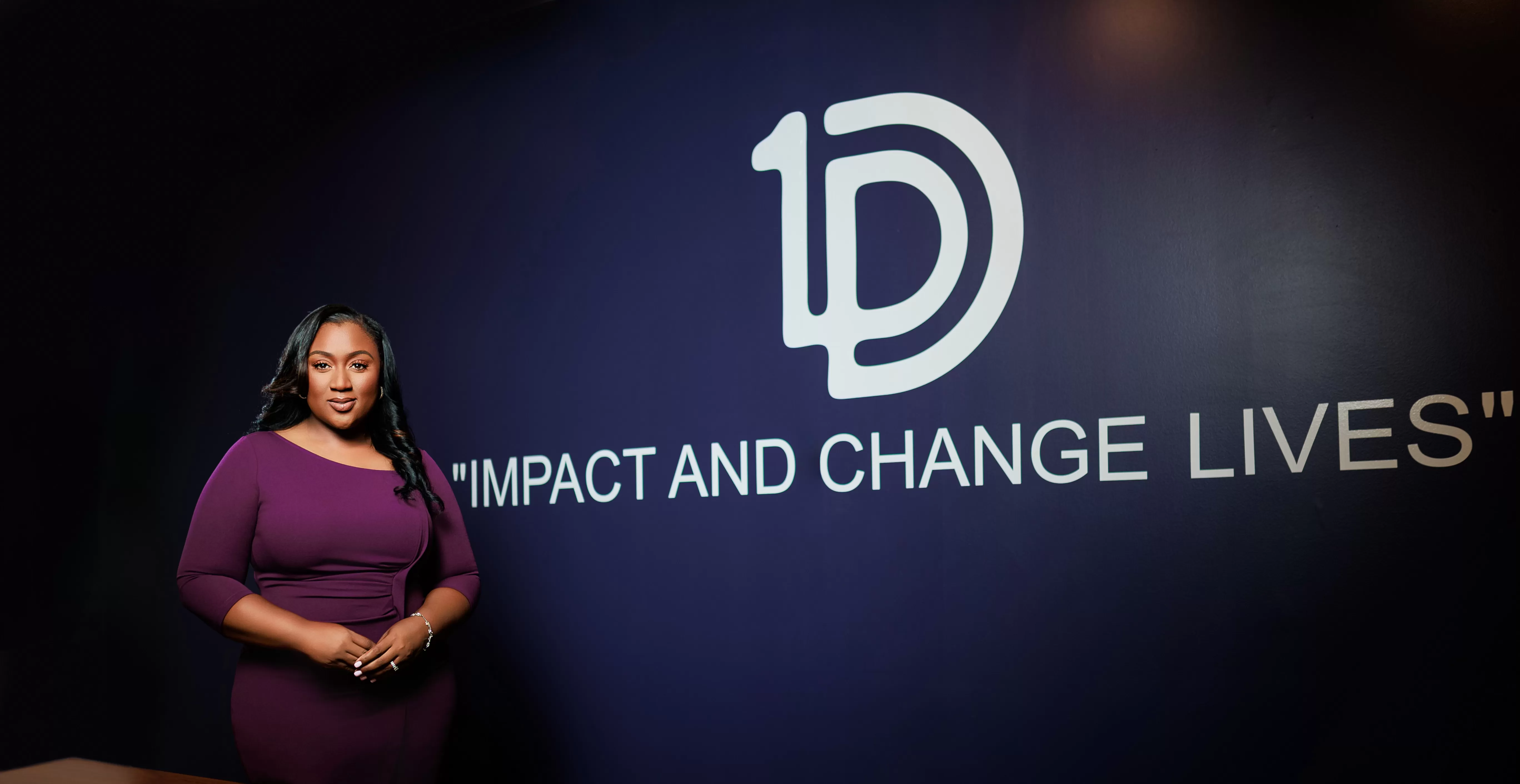 Photo of One Detroit Credit Union CEO Portia Powell standing against a purple wall with the phrase "Impact and Change Lives" painted underneath the credit union logo
